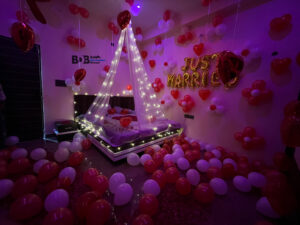 Romantic just married room decoration with red and white balloons and fairy light canopy bed setup in Bhopal
