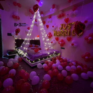 Romantic just married room decoration with red and white balloons and fairy light canopy bed setup in Bhopal