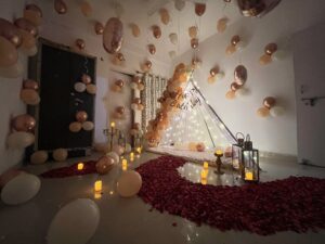 Luxury rose gold romantic couple bedroom decoration with balloons fairy lights and rose petals in Bhopal